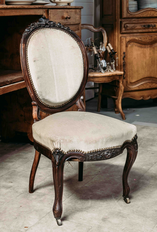 Lovely antique French salon chair in a dusty cream upholstery and on small front castor wheels